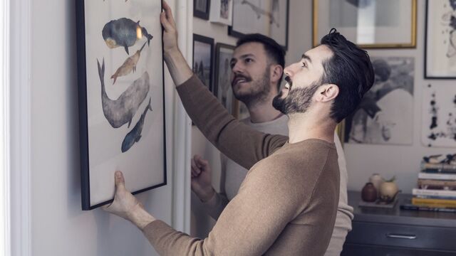 Male couple hanging painting on wall - SMALL
